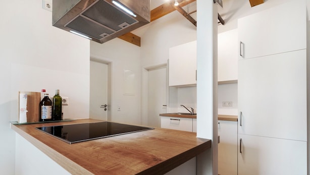 A modern kitchen with a wooden countertop, a built-in stove, white cabinets, and a stainless steel range hood. - Holiday Apartment 'Kirsche' with Wi-Fi (Sasbach am Kaiserstuhl)