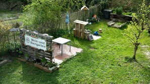 A garden with a wooden fence, a sign reading 'Wein-und Biergarten,' and a small wooden structure. - Holiday Apartment 'Kirsche' with Wi-Fi (Sasbach am Kaiserstuhl)