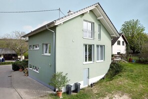 A two-story house with a sloped roof, a front porch, and a small front yard with potted plants. - Holiday Apartment 'Kirsche' with Shared Terrace, Shared Garden and Wi-Fi (Sasbach am Kaiserstuhl)