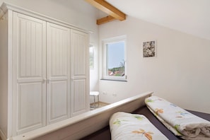 A bedroom with a bed, a window, a wardrobe, and a small picture on the wall. - Holiday Apartment 'Kirsche' with Shared Terrace, Shared Garden and Wi-Fi (Sasbach am Kaiserstuhl)