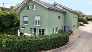 A two-story building with a green facade, multiple windows, and a small balcony. - Holiday Apartment 'Kirsche' with Wi-Fi (Sasbach am Kaiserstuhl)