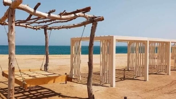 A beach with a wooden swing set and a white structure. - Charming 1-Bed Chalet in Hurghada (Hurghada)