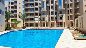 A swimming pool surrounded by a multi-story building with balconies. - Charming 1-Bed Chalet in Hurghada (Hurghada)