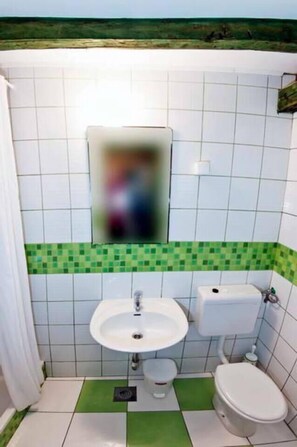 Et badeværelse med vask, toilet og spejl.