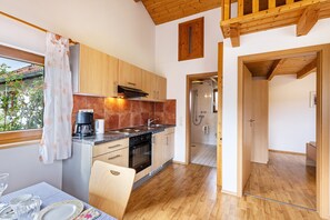 A modern kitchen with wooden cabinets, a coffee maker, and a dining table set for two. - Holiday Home "Katrin" with Private Terrace & Wi-Fi (Bad Urach)
