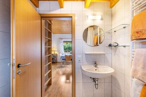 A bathroom with a wooden door, a sink, a mirror, and a towel rack. - Holiday Home "Katrin" with Private Terrace & Wi-Fi (Bad Urach)