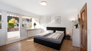 A bedroom with a bed, a radiator, a window, and a door. - Studio Apartment "Paulas" with Balcony and Wi-Fi (Füssen)