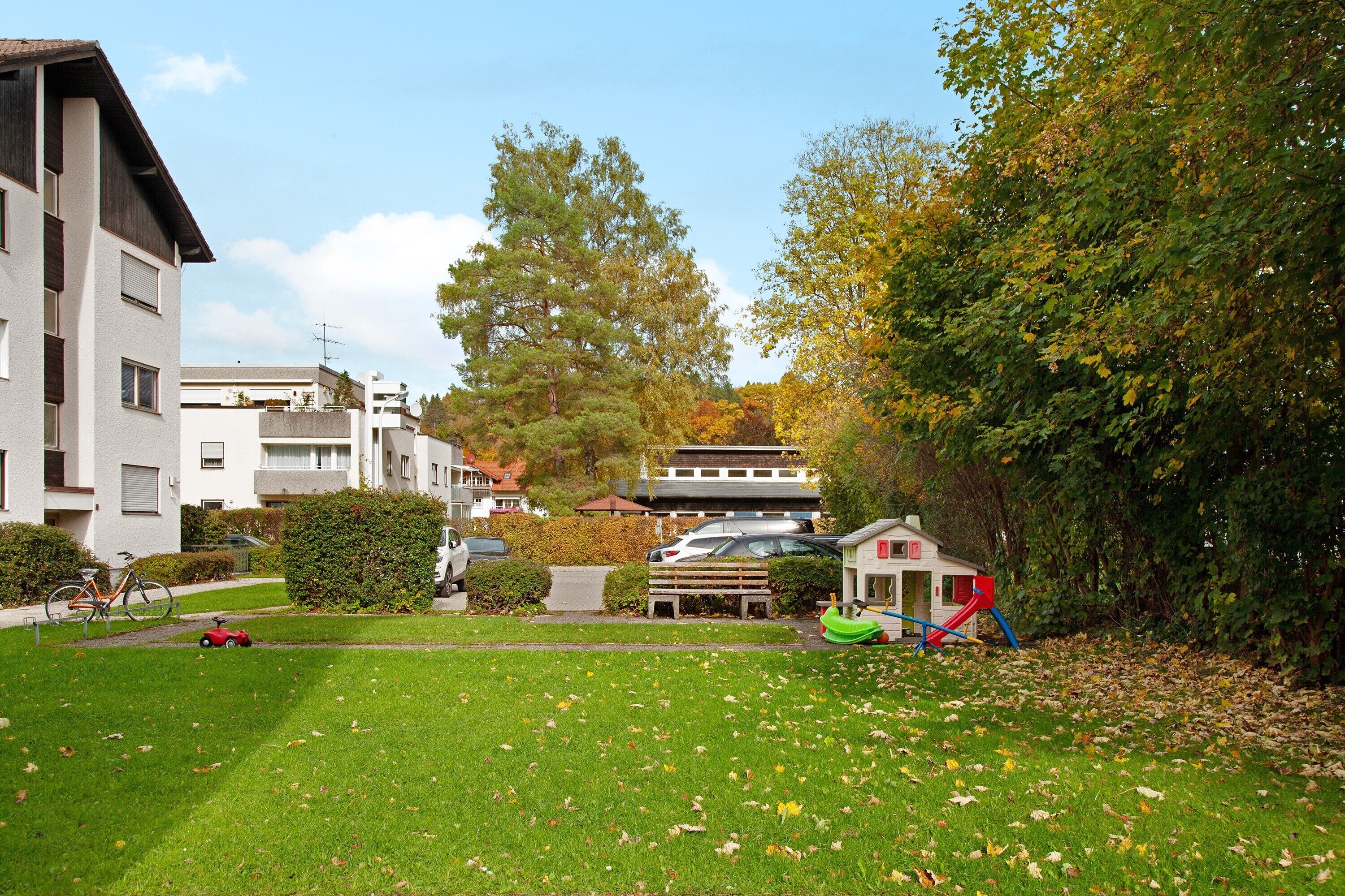 Zona residencial con césped, una estructura de juegos infantiles y una bicicleta.