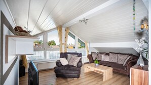 Un salon moderne comprenant un canapé, un fauteuil, une table basse en bois et un téléviseur.