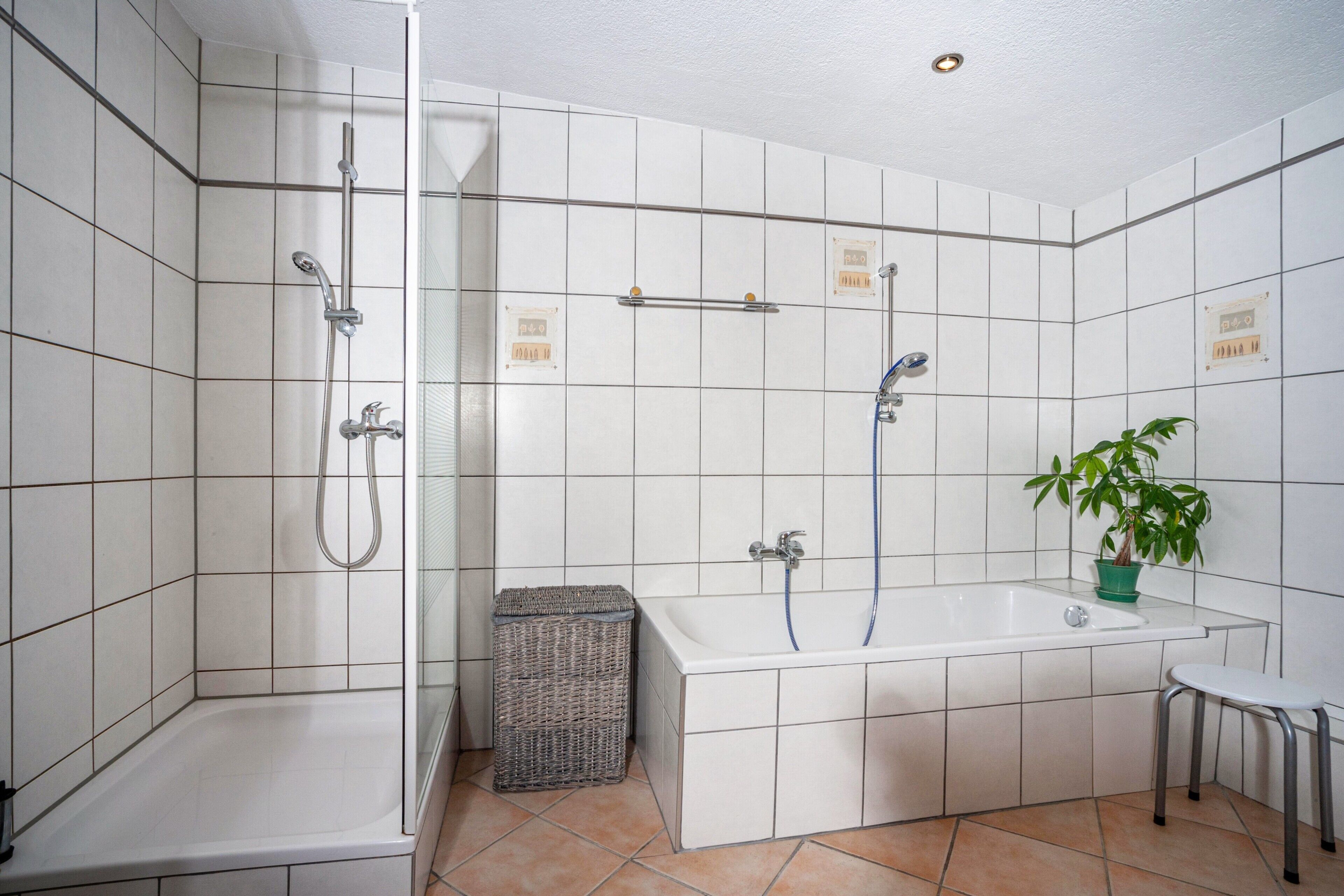 A bathroom with a shower, bathtub, and a small stool.