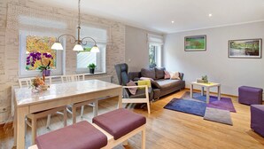 A modern living room with a dining area, a sofa, a small table, and a window with a view.