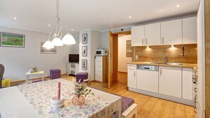 A modern kitchen with white cabinets, a wooden countertop, and a dining area with a floral tablecloth.