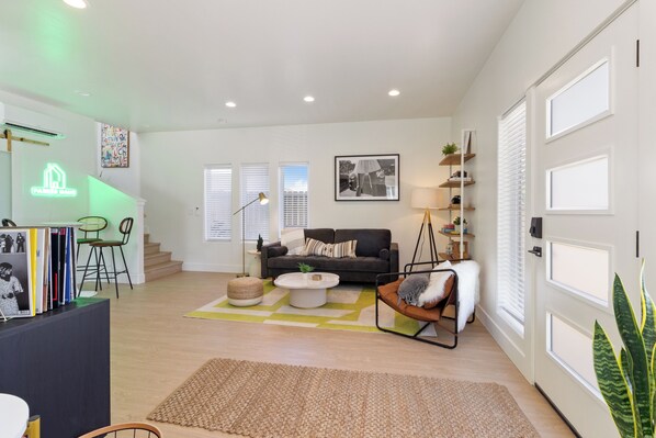 A modern living room with a sofa, coffee table, and a staircase leading to another level. - Modern Downtown Talent Dream (Talent)