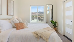 A bedroom with a large bed, a view of the mountains, a mirror, and a potted plant. - Modern Downtown Talent Dream (Talent)