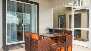A glass-enclosed balcony with wicker furniture and a black pot. - Wonderful 6bd 5bat w Golf Course Championsgate (Kissimmee)