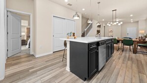 A modern kitchen with a central island, black cabinetry, and pendant lighting. - Brand New Windsor Island 5 Suites (Davenport)