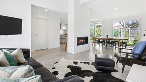 Un salon moderne avec un canapé en cuir noir, un tapis en peau de vache et une chemin ée.