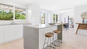 Une cuisine moderne dotée d’un grand îlot central, de tabourets de bar et d’un coin repas avec une table et des chaises.