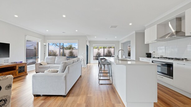 A modern kitchen with white cabinets, a central island, and a dining area with bar stools. - Seagrove Getaway in Cowes (Cowes)