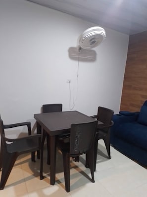 A dining area with a table and chairs, a ceiling fan, and a blue sofa in the background. - Room-juliana Tourist House (Cartagena)