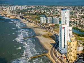 A coastal cityscape with high-rise buildings, a beach, and a road running parallel to the shore. - Room-juliana Tourist House (Cartagena)