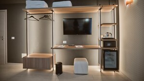 Ein modernes Hotelzimmer mit Bett, Schreibtisch, Fernseher, Minibar und Kleiderschrank.