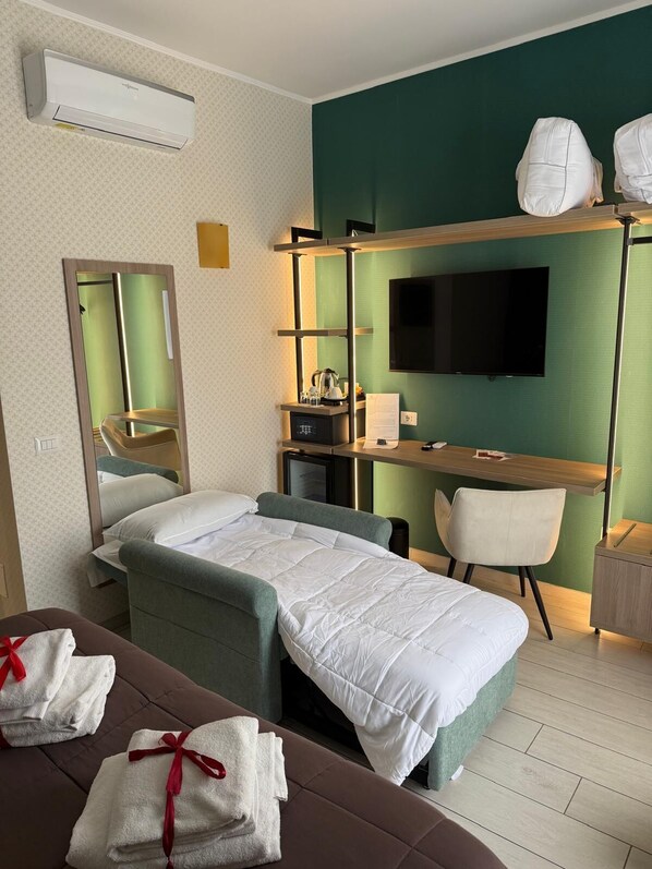 Una habitación de hotel con una cama, un escritorio, una silla, un televisor y un equipo de aire acondicionado.
