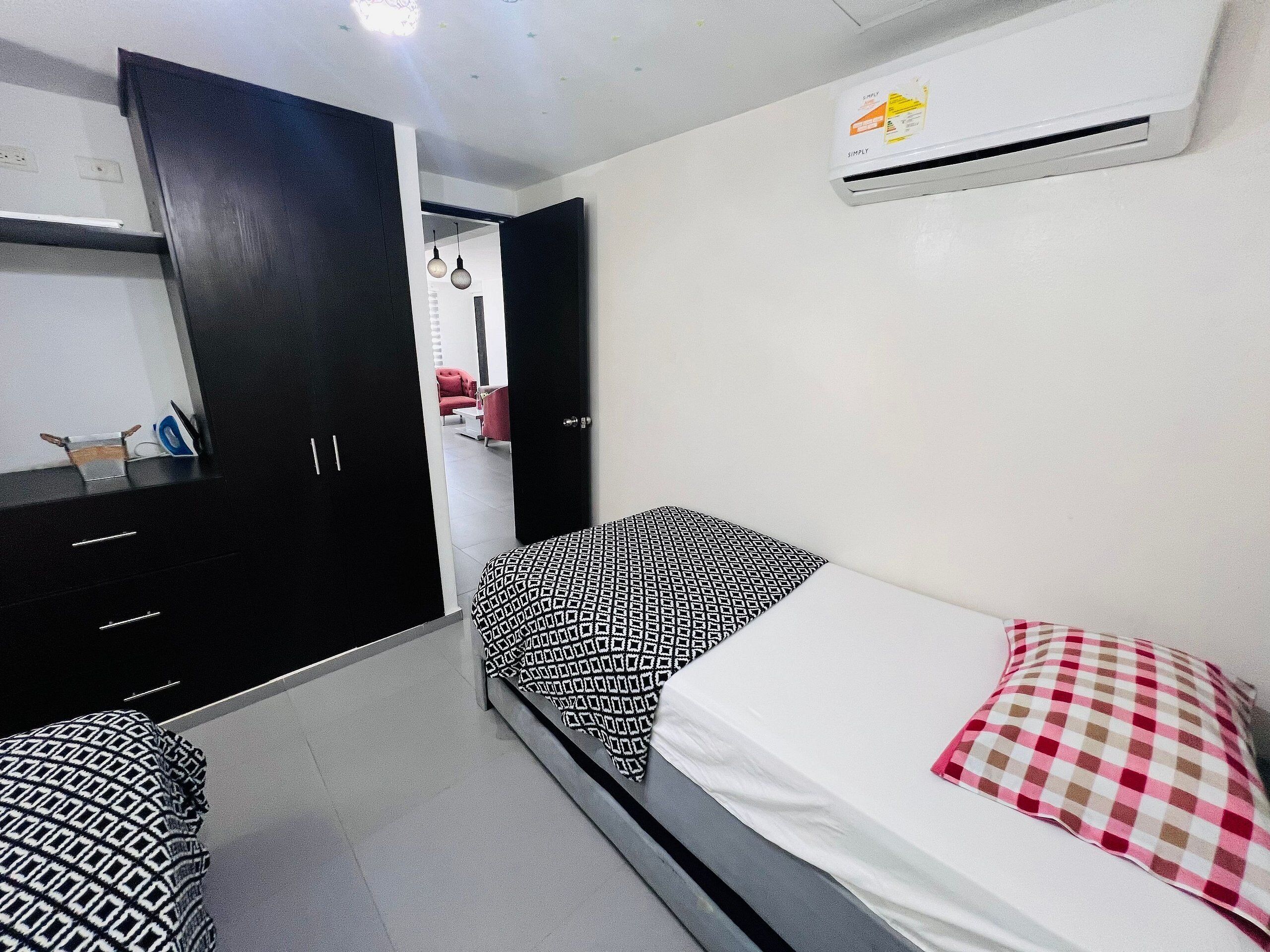 Een slaapkamer met een bed, een kledingkast, een bureau en een airconditioning.