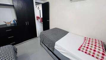 Een slaapkamer met een bed, een kledingkast, een bureau en een airconditioning.