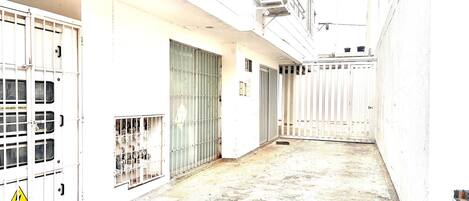 A corridor with a metal gate, a door, and an air conditioning unit.