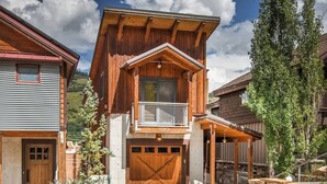 Een houten huis met twee verdiepingen, een balkon, een garage en een overdekte veranda.
