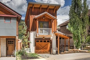 A two-story wooden house with a balcony, a garage, and a covered porch.