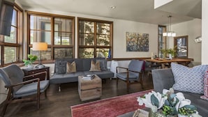 Een ruime woonkamer met een grote bank, fauteuils, een salontafel en een eethoek met een tafel en stoelen.