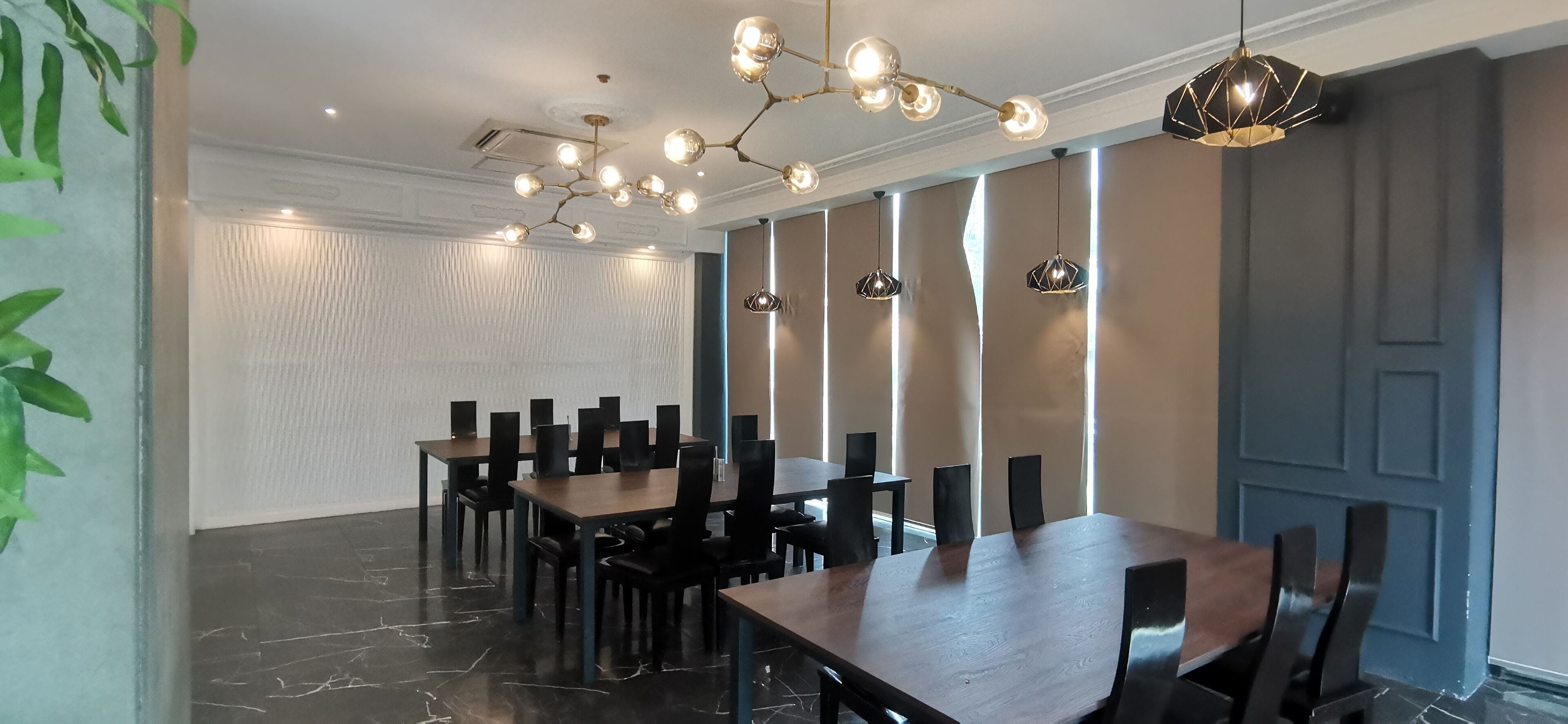 A conference room with a long table, multiple chairs, and pendant lighting.