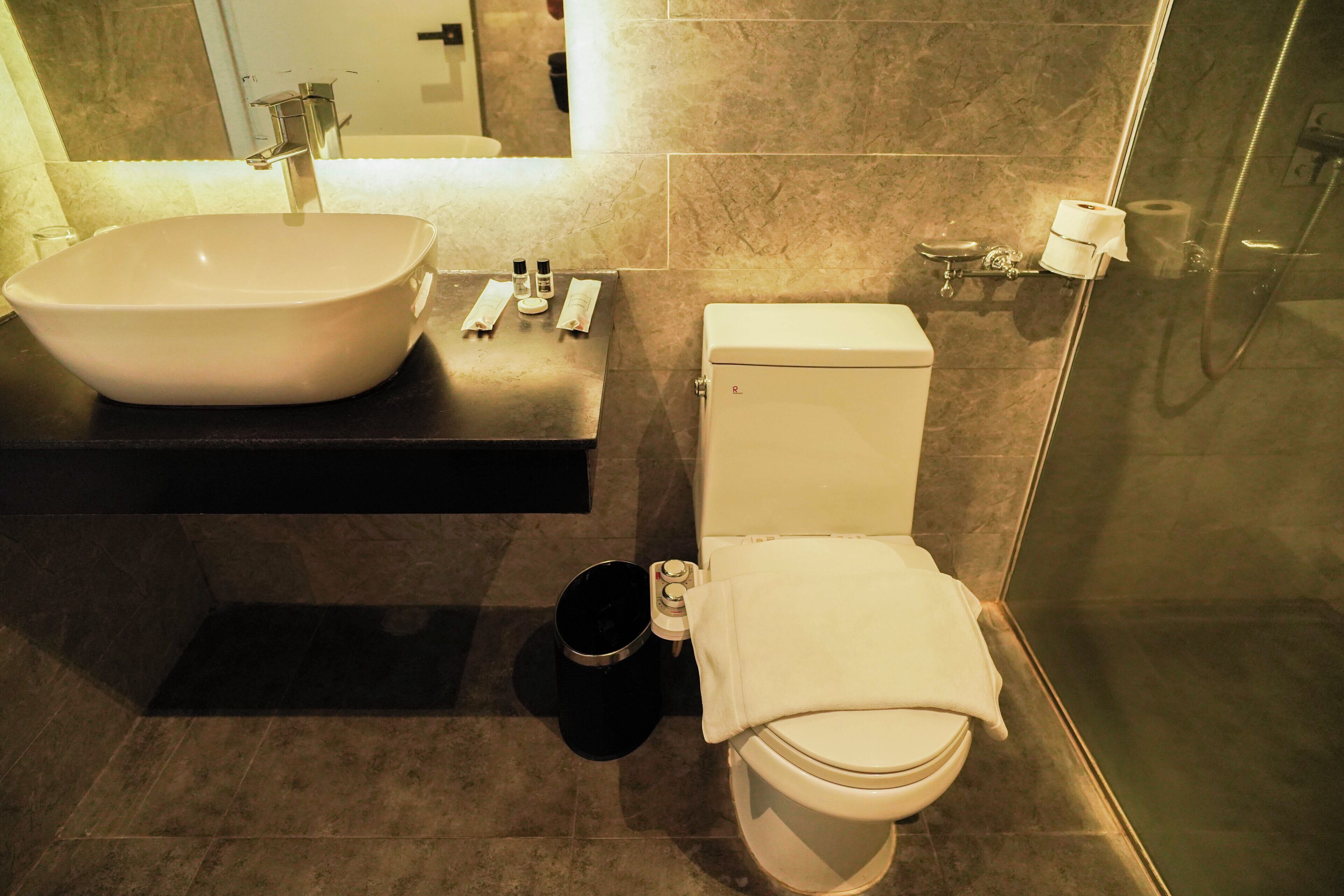 Un baño moderno con un lavamanos tipo recipiente, inodoro y zona de ducha.