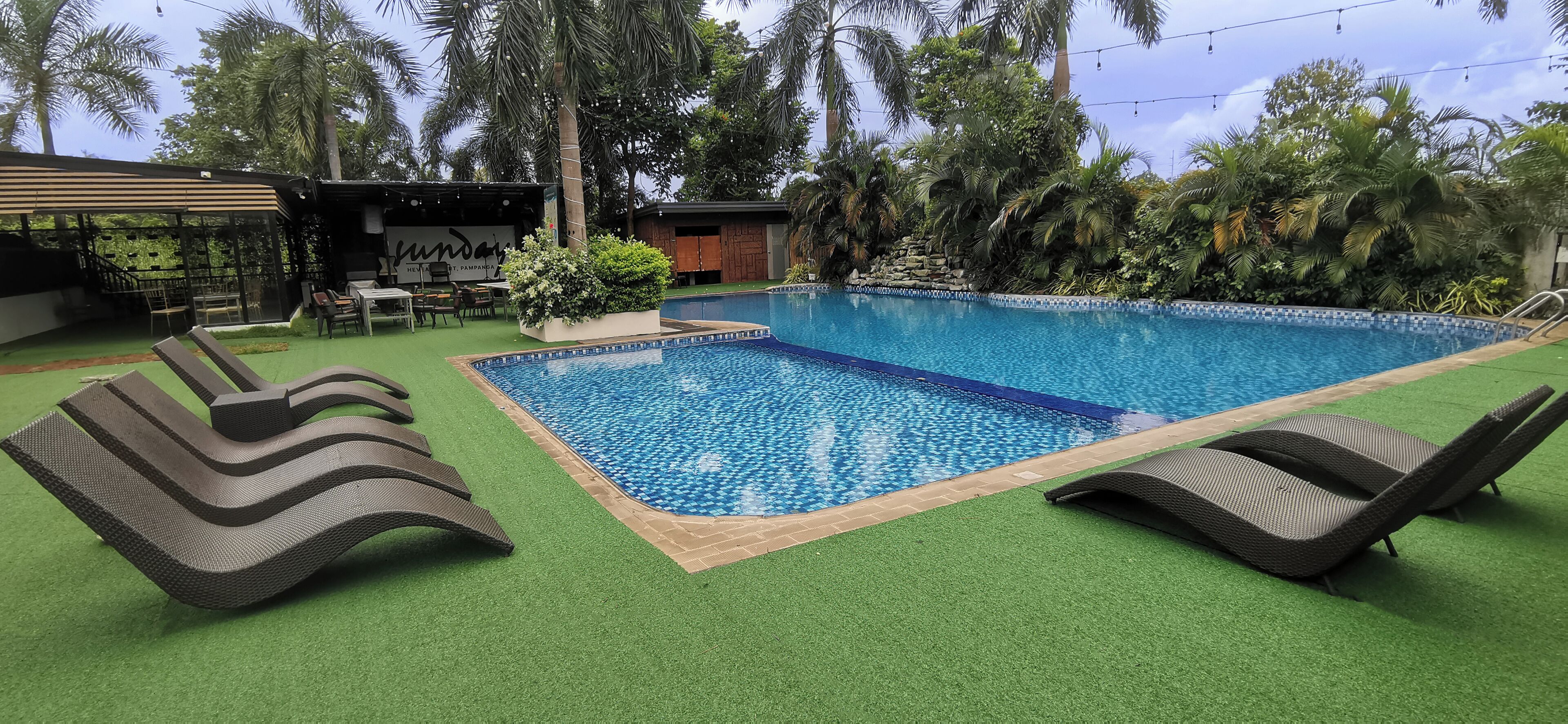 A swimming pool with lounge chairs and a bar area with outdoor seating.