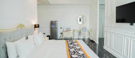 Una habitación de hotel con una cama grande, un escritorio, una silla, un televisor y un minibar.