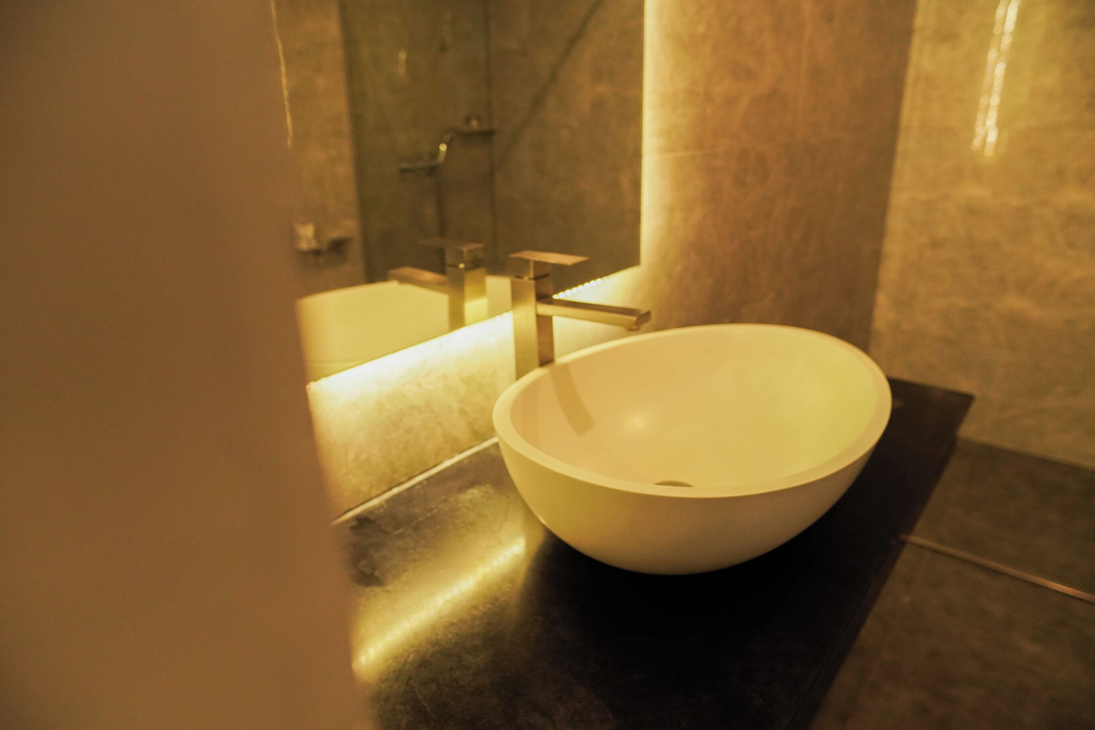 Une salle de bain moderne avec un grand lavabo sur pied blanc, un meuble-lavabo élégant et une douche à parois de verre.