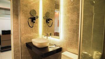 Un baño moderno con un lavamanos grande, dos espejos montados en la pared y una cabina de ducha de vidrio.