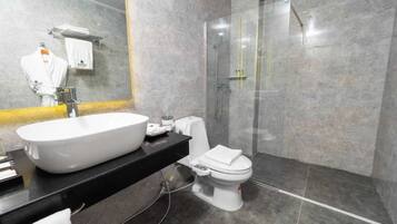 A modern bathroom with a large white sink, a toilet, and a glass-enclosed shower.