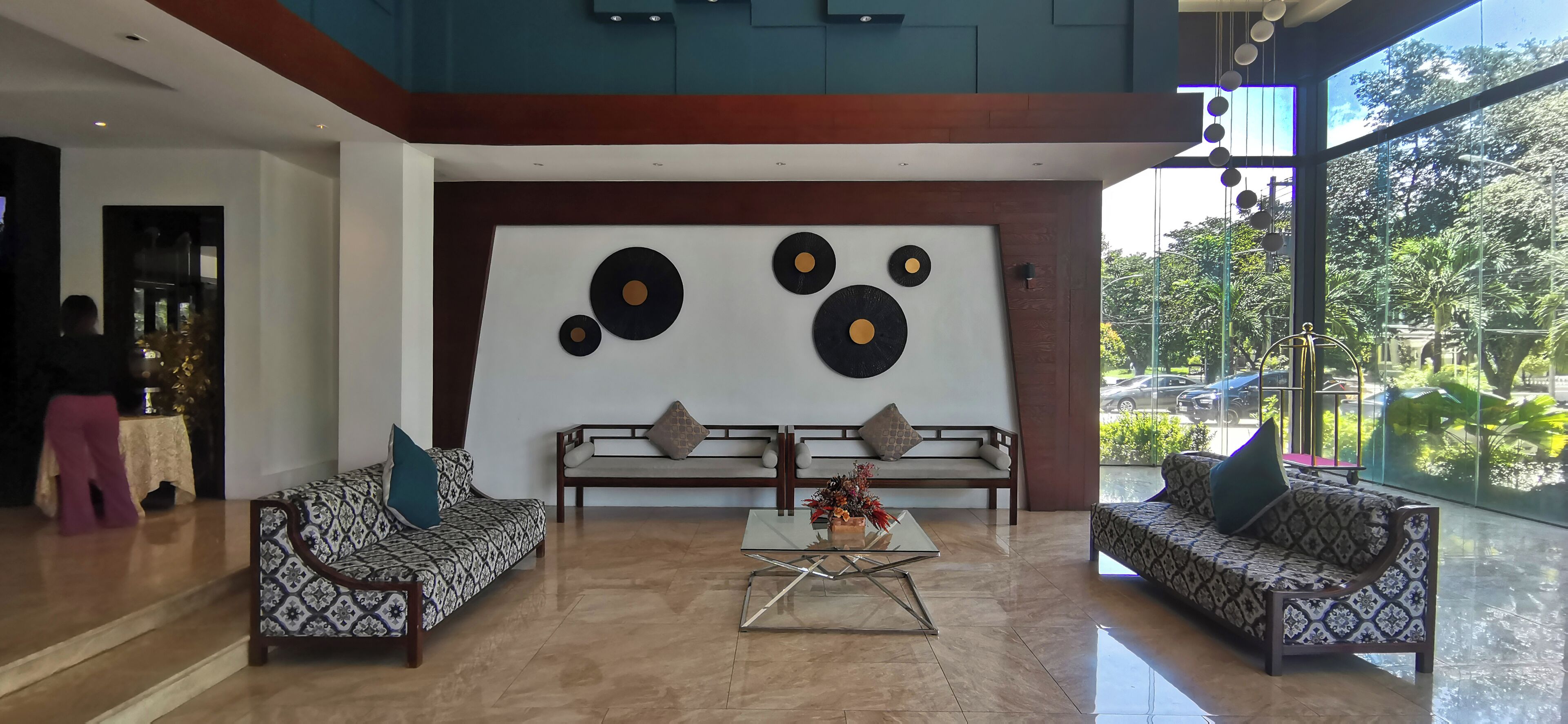 Eine großzügige Lobby mit zwei gemusterten Sofas, einem Glastisch und einer Wand mit kreisförmigen Mustern.
