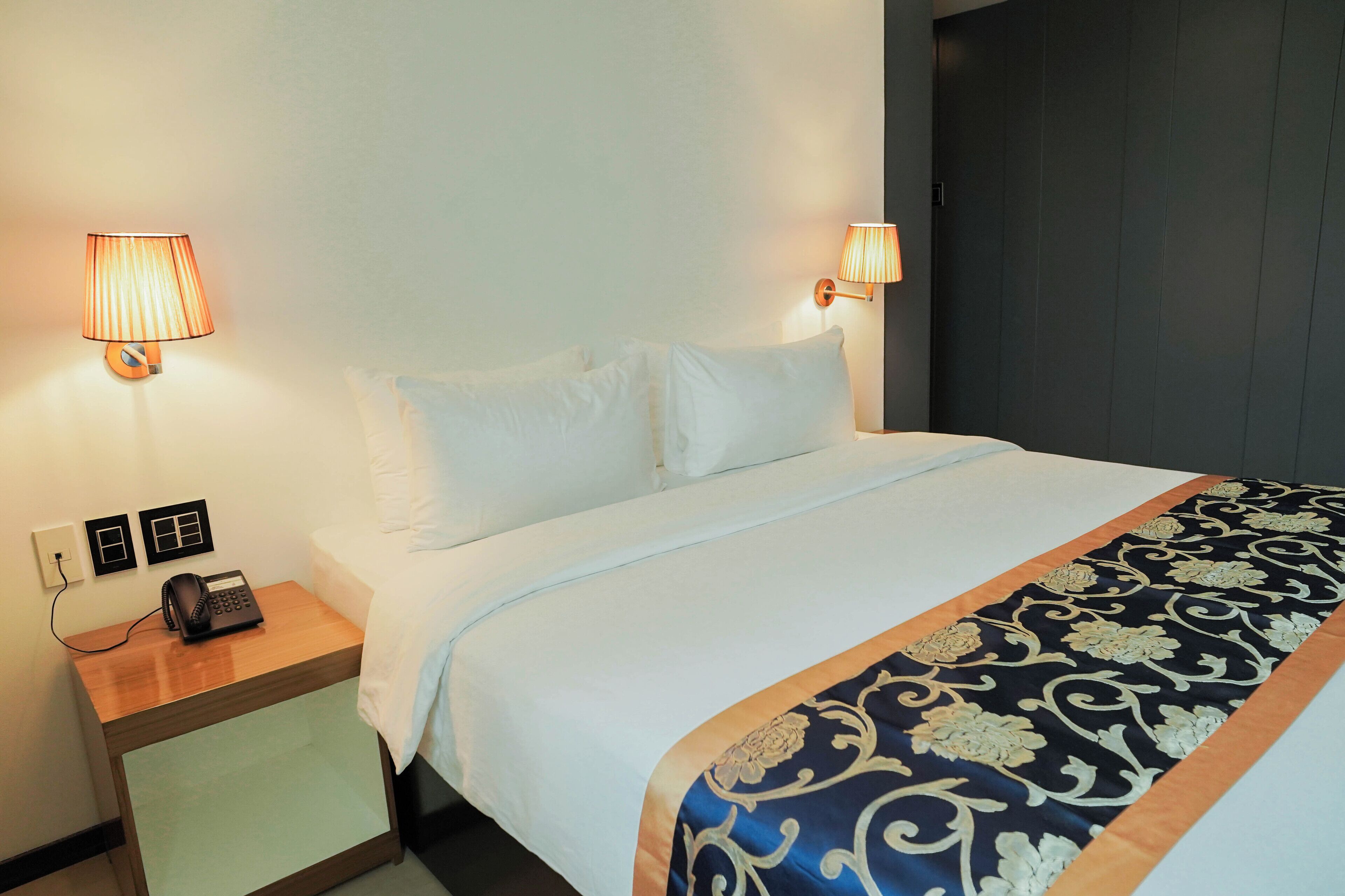 Une chambre d’hôtel avec un lit, deux lampes de chevet, un téléphone et une table de chevet.