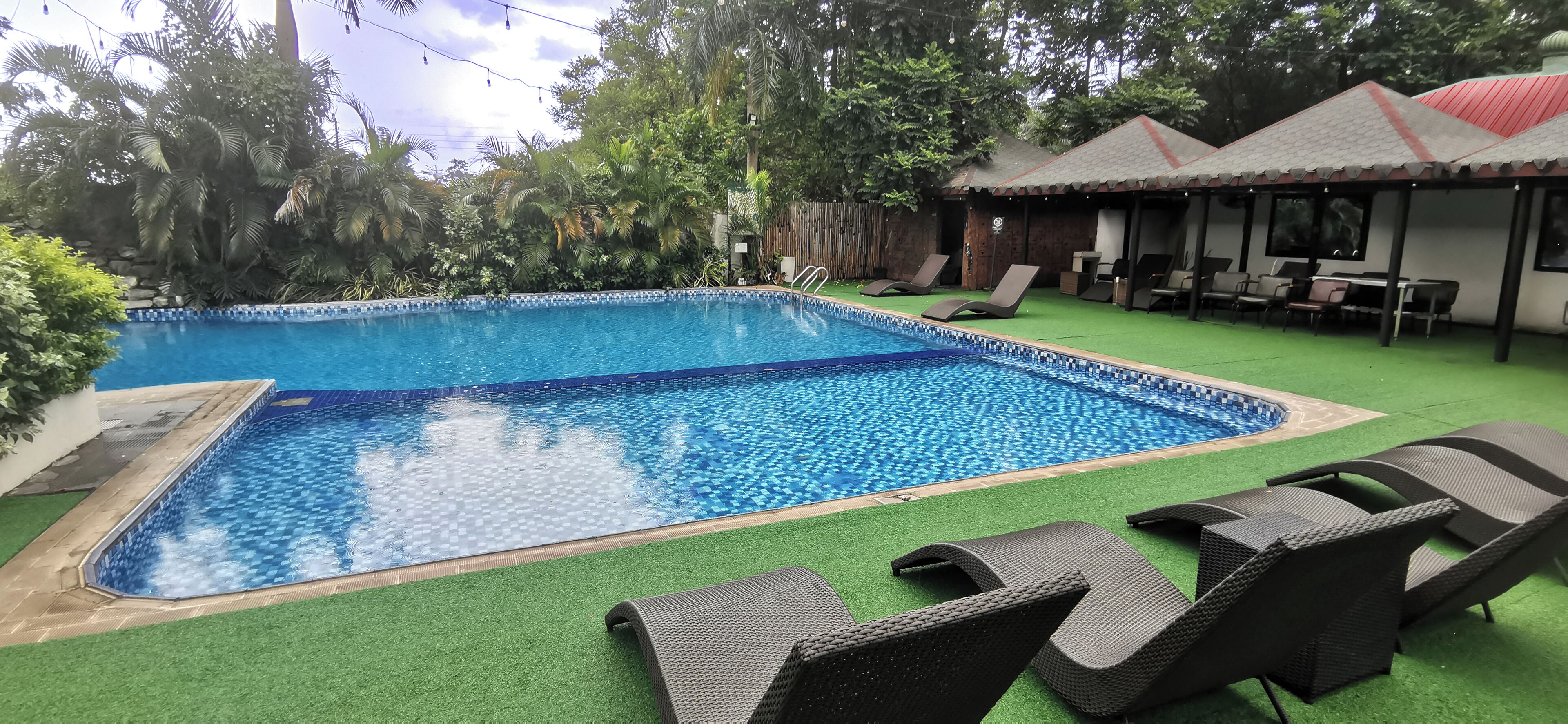 A swimming pool with lounge chairs and a covered seating area.