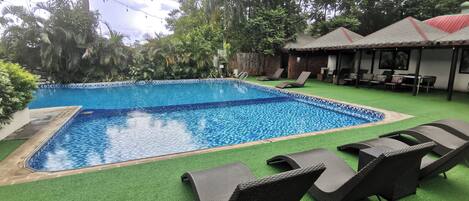 A swimming pool with lounge chairs and a covered seating area.