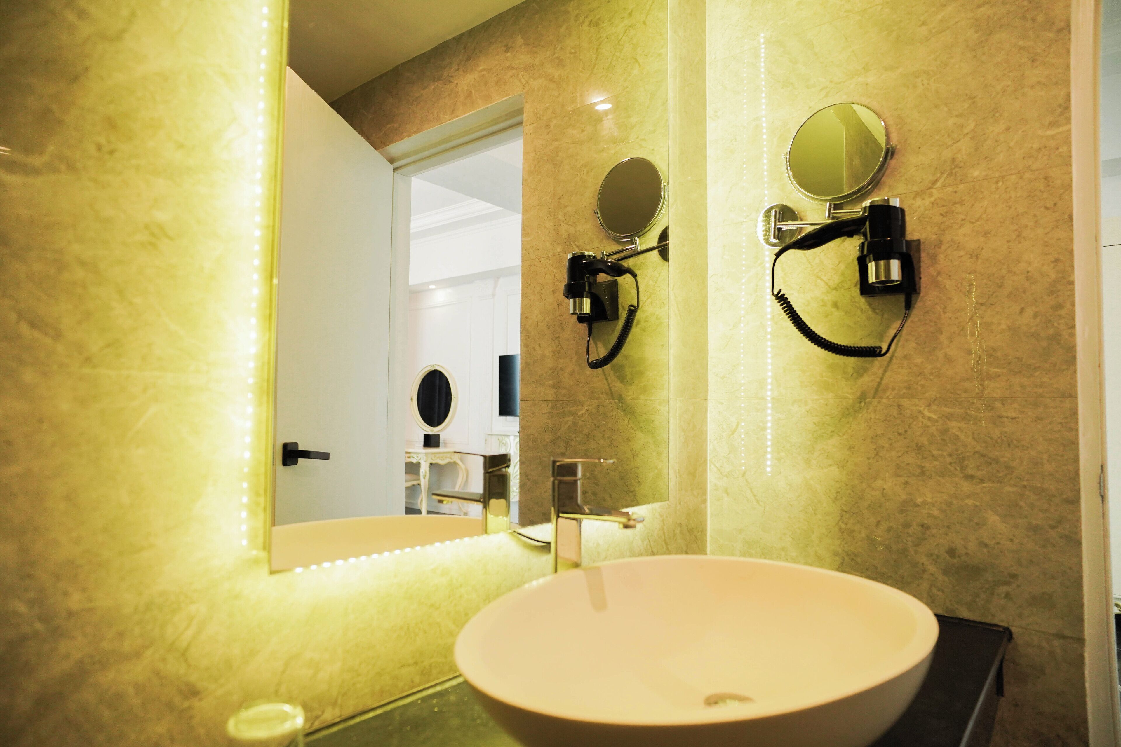 A bathroom with a large mirror, two wall-mounted lights, and a round sink.