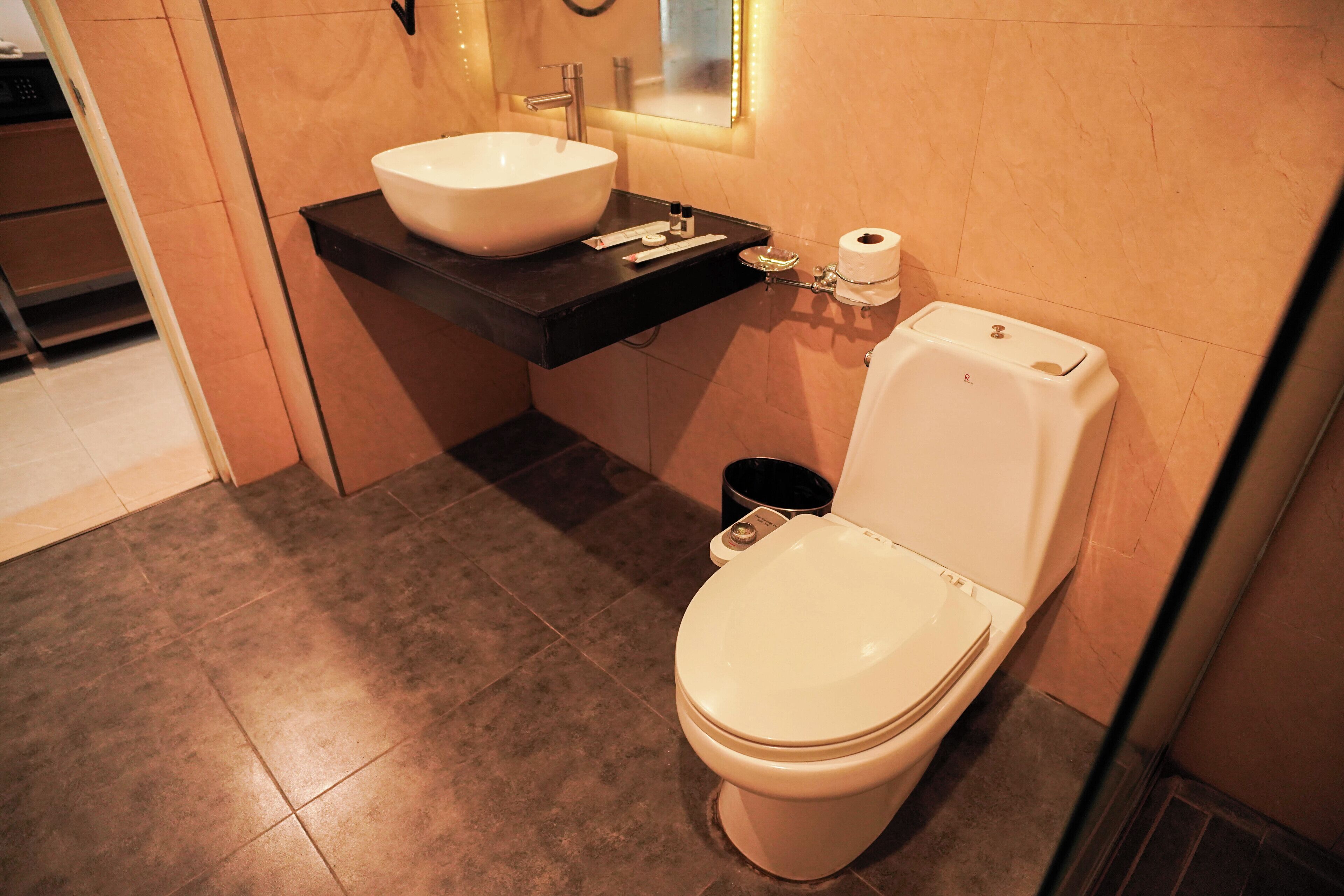 A modern bathroom with a white toilet, a large white sink, and a black countertop.