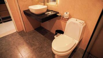 A modern bathroom with a white toilet, a large white sink, and a black countertop.