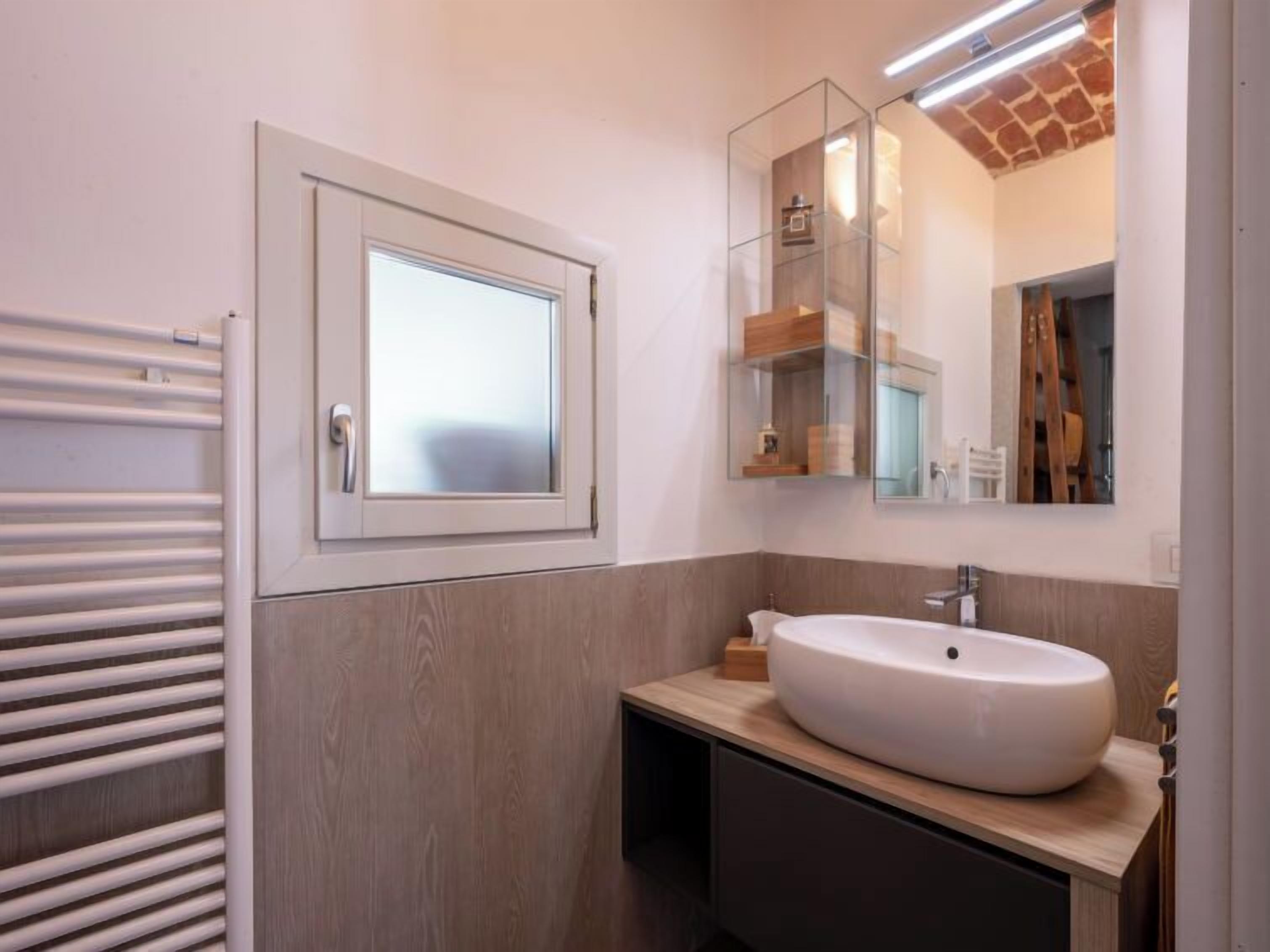 A modern bathroom with a large window, a built-in sink, and a mirror above the sink.