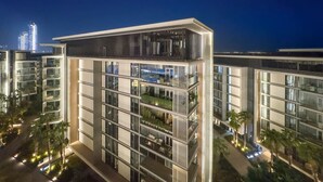 A modern multi-story building with balconies, large windows, and a flat roof.