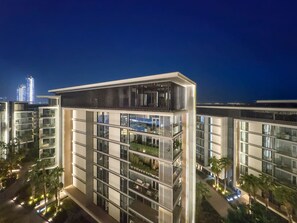 A modern multi-story building with balconies, large windows, and a flat roof.